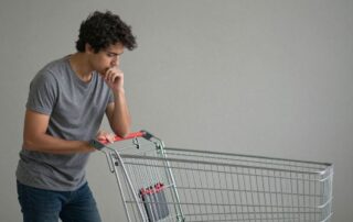 Prázdný nákupní košík a zamyšlený člověk